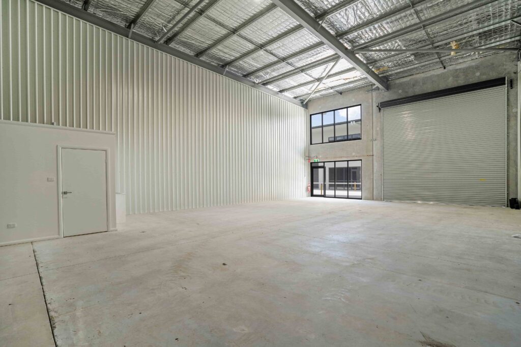 Interior of a completed AJA industrial unit at Rutherford, with a steel-framed insulated roof, roller door and two-level office glazing