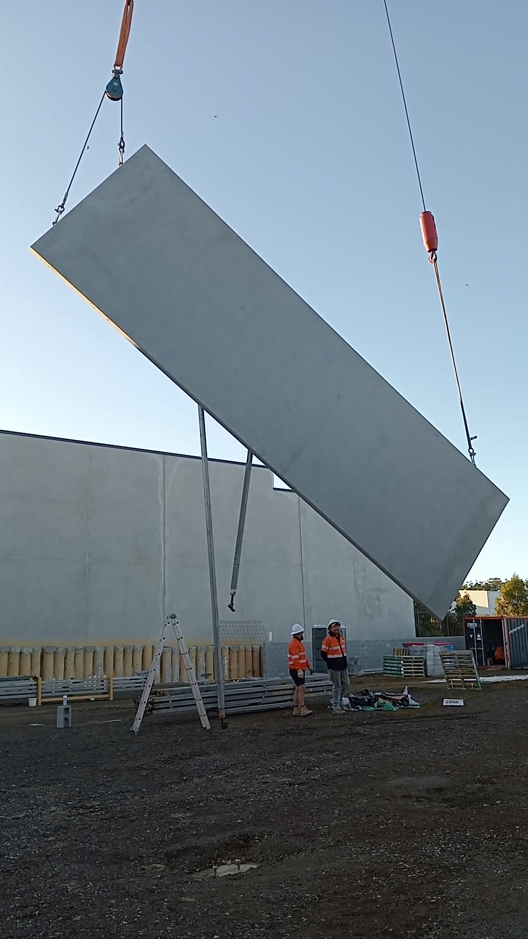 Concrete wall panel being lifted into place by crane on an AJA industrial site